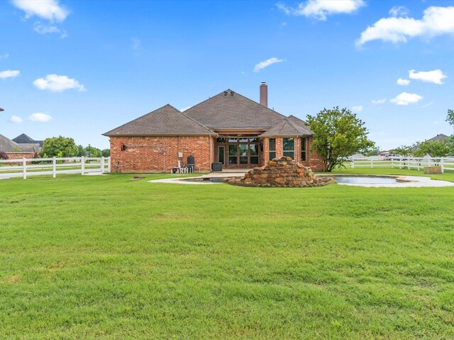 rear view of property featuring a lawn, fence, and brick siding
