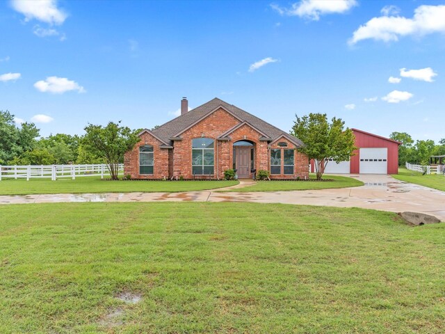 view of front facade with a chimney, brick siding, fence, a front lawn, and concrete driveway