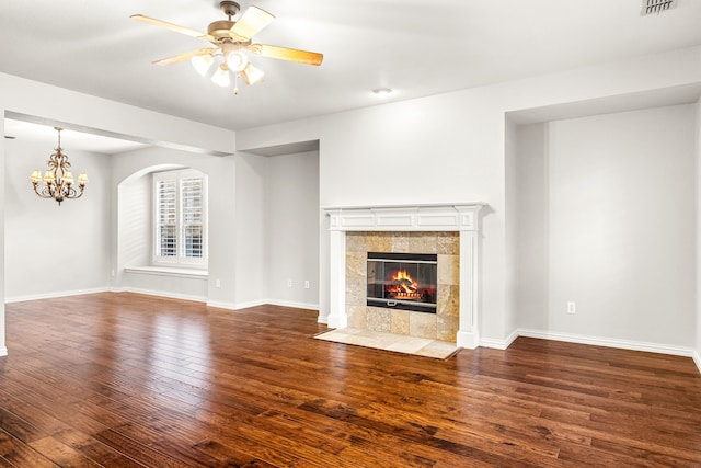 unfurnished living room with baseboards, ceiling fan with notable chandelier, wood finished floors, and a tile fireplace