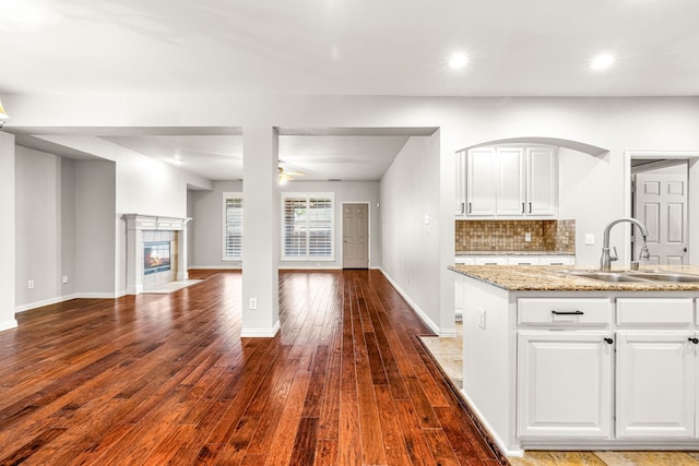 kitchen featuring dark wood-style flooring, a sink, a ceiling fan, open floor plan, and white cabinetry