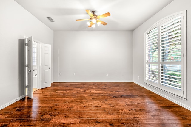 spare room featuring baseboards, visible vents, a ceiling fan, and dark wood-type flooring