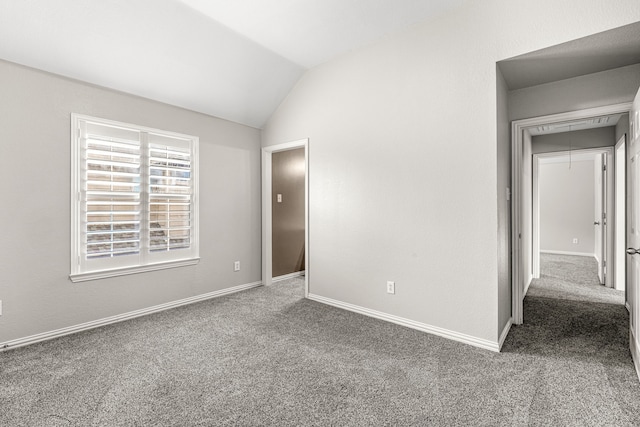 unfurnished bedroom featuring carpet floors, attic access, baseboards, and lofted ceiling