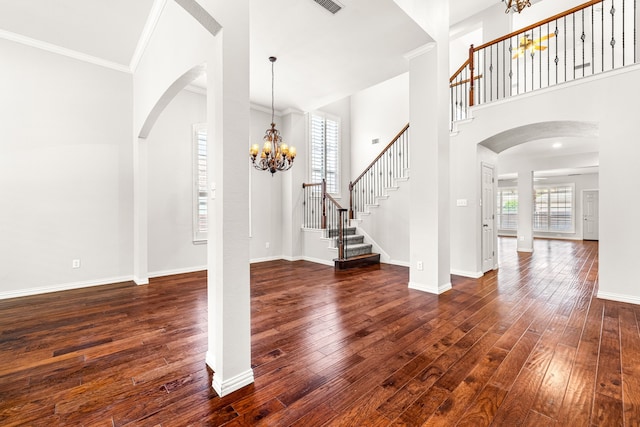 entrance foyer featuring arched walkways, stairway, dark wood-style floors, a chandelier, and a high ceiling