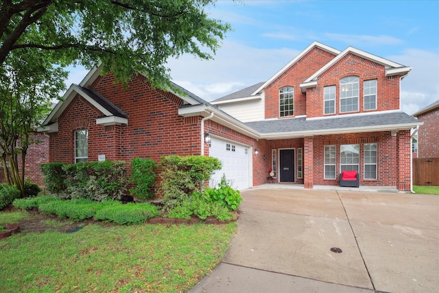 traditional-style home with driveway, roof with shingles, a garage, brick siding, and fence