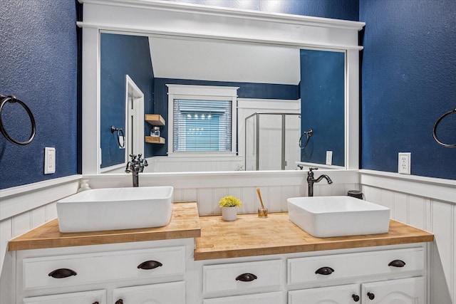 full bath featuring vanity, a textured wall, a wainscoted wall, and a stall shower