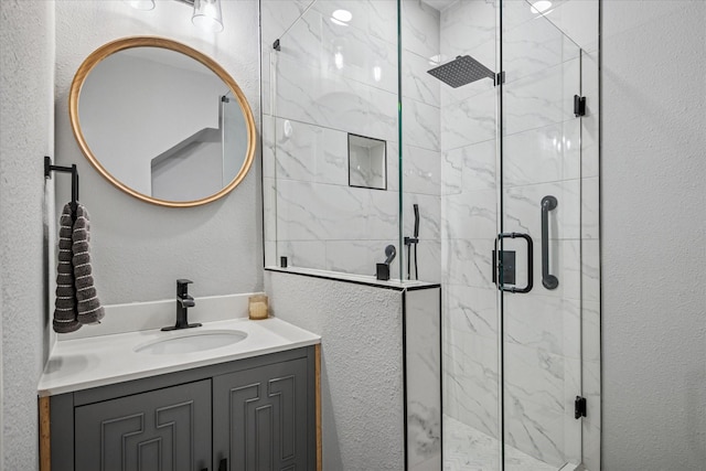 full bathroom featuring a textured wall, a shower stall, and vanity