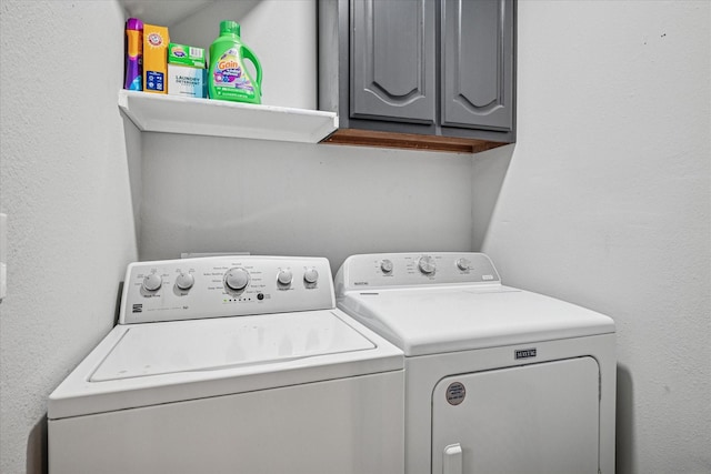 clothes washing area featuring cabinet space and washer and clothes dryer