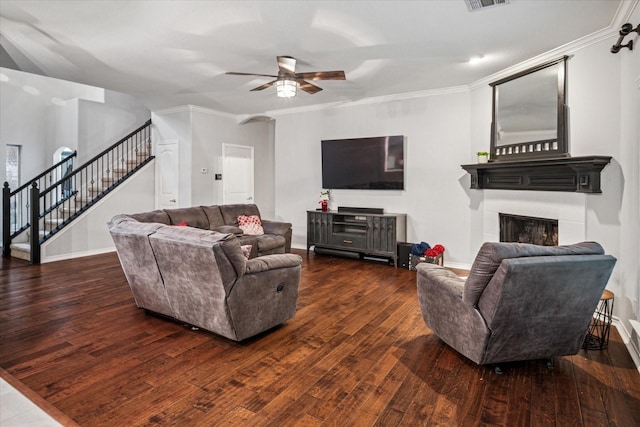 living room featuring crown molding, wood finished floors, a fireplace, stairway, and a ceiling fan