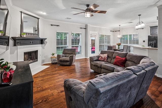 living room with plenty of natural light, ornamental molding, a ceiling fan, and a tile fireplace