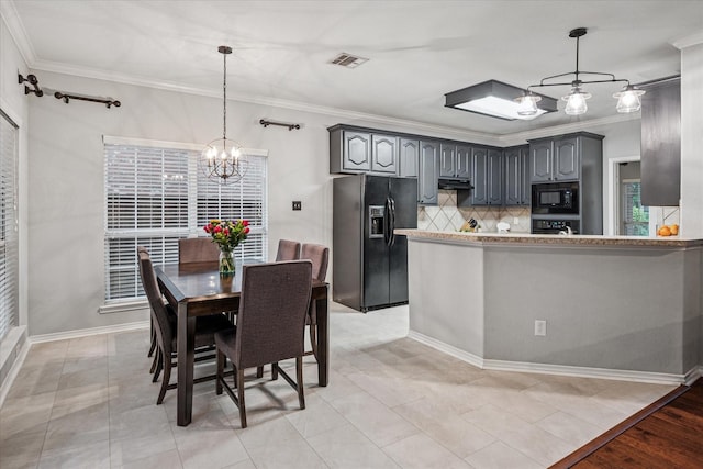 kitchen featuring crown molding, a chandelier, decorative backsplash, under cabinet range hood, and black appliances
