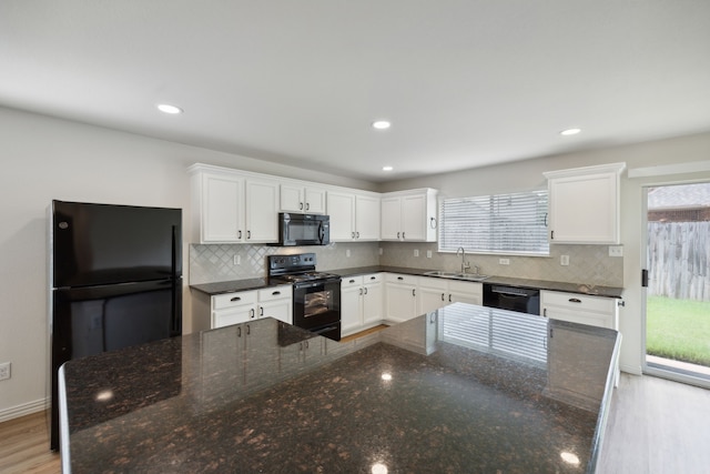 kitchen with white cabinets, decorative backsplash, a sink, and black appliances