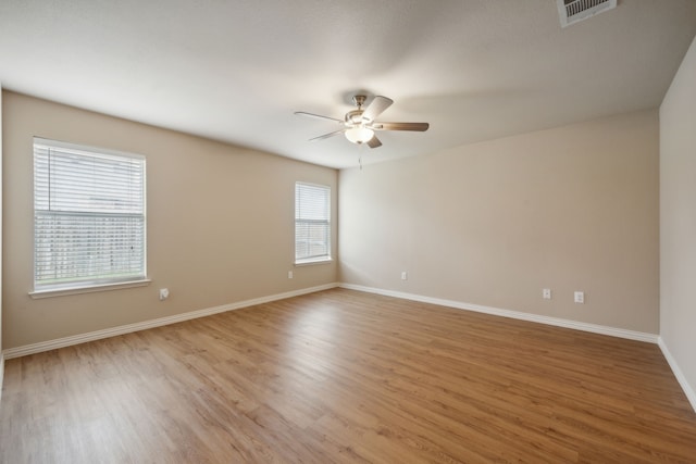 unfurnished room with baseboards, ceiling fan, light wood finished floors, and visible vents
