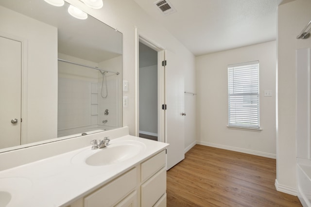 bathroom with a sink, double vanity, baseboards, wood finished floors, and visible vents