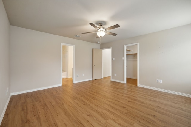 unfurnished bedroom featuring baseboards, visible vents, a spacious closet, and light wood finished floors