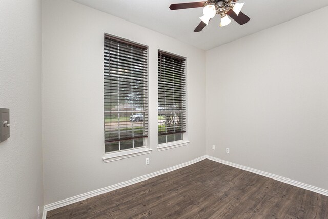 unfurnished room featuring baseboards, a ceiling fan, and dark wood finished floors