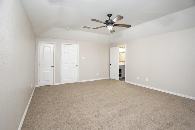unfurnished bedroom with visible vents, baseboards, connected bathroom, carpet, and vaulted ceiling