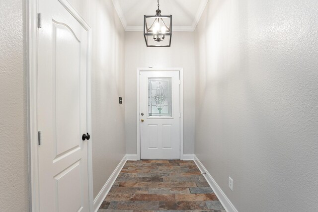 doorway featuring baseboards, ornamental molding, stone finish floor, and a chandelier