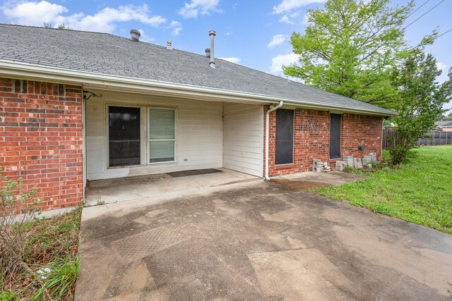 rear view of property featuring a yard, brick siding, fence, and a patio area