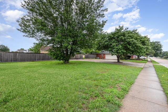 view of yard featuring fence and aphalt driveway