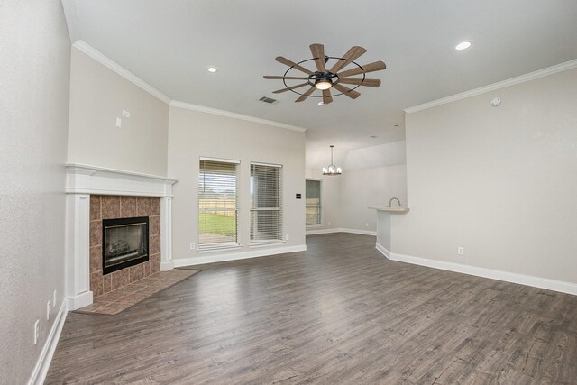 unfurnished living room with ornamental molding, wood finished floors, ceiling fan with notable chandelier, and a fireplace