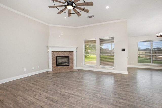 unfurnished living room with visible vents, a tiled fireplace, baseboards, ceiling fan with notable chandelier, and ornamental molding