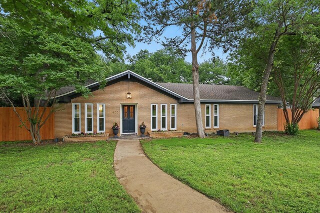 single story home featuring brick siding, fence, and a front lawn