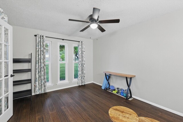 empty room with a textured ceiling, baseboards, a ceiling fan, and wood finished floors
