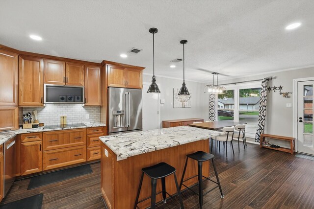 kitchen featuring dark wood-style flooring, a center island, stainless steel appliances, tasteful backsplash, and visible vents
