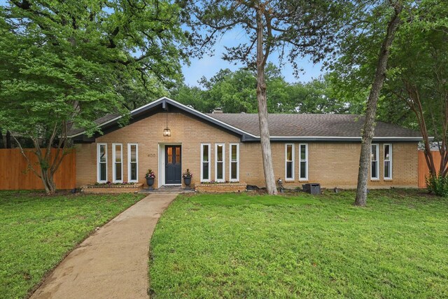 view of front facade with brick siding, fence, and a front yard
