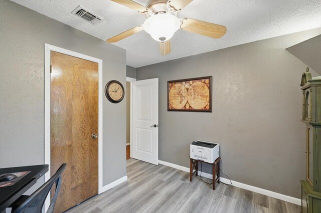office space with visible vents, baseboards, ceiling fan, and light wood-type flooring