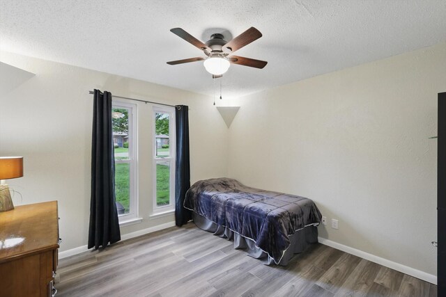 bedroom featuring a textured ceiling, baseboards, a ceiling fan, and wood finished floors