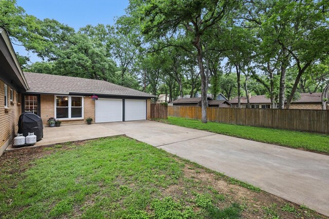 view of yard featuring an attached garage, fence, and driveway