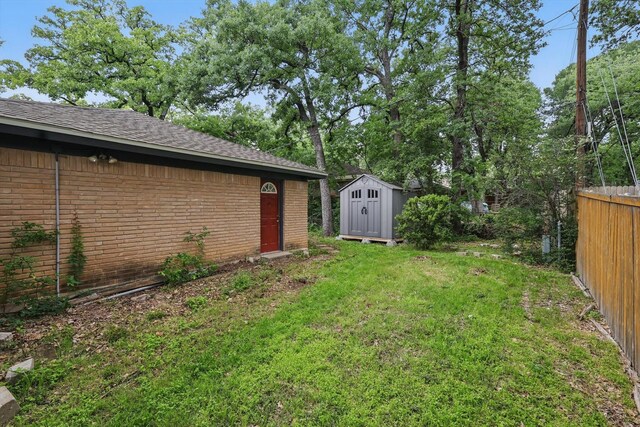 view of yard featuring a storage shed, fence, and an outdoor structure