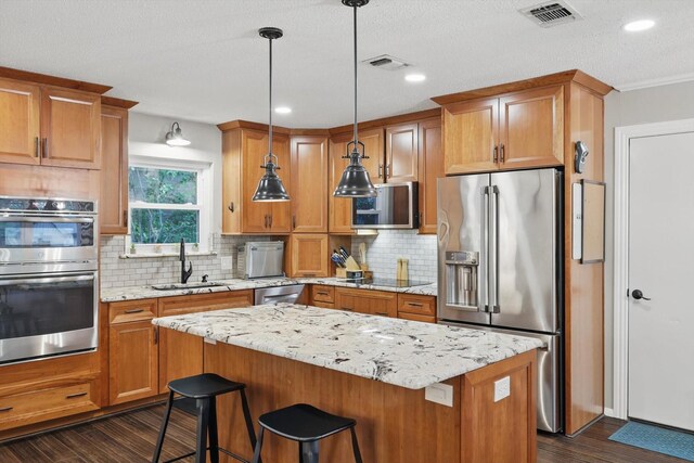kitchen with appliances with stainless steel finishes, a sink, visible vents, and dark wood-type flooring