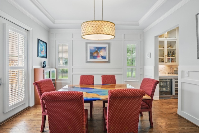dining room with bar, crown molding, wood finished floors, wine cooler, and a decorative wall