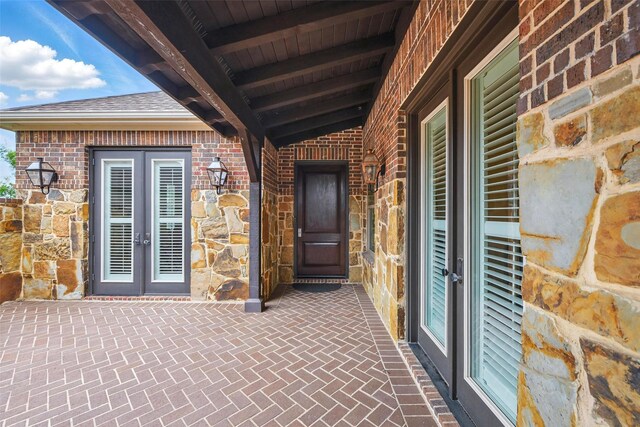 entrance to property featuring brick siding, french doors, and stone siding