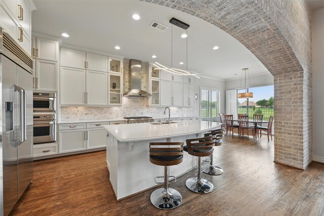 kitchen with visible vents, light countertops, wall chimney exhaust hood, a sink, and appliances with stainless steel finishes