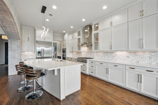 kitchen featuring appliances with stainless steel finishes, a sink, wall chimney exhaust hood, and tasteful backsplash