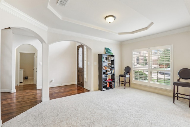 sitting room with arched walkways, visible vents, ornamental molding, and a raised ceiling