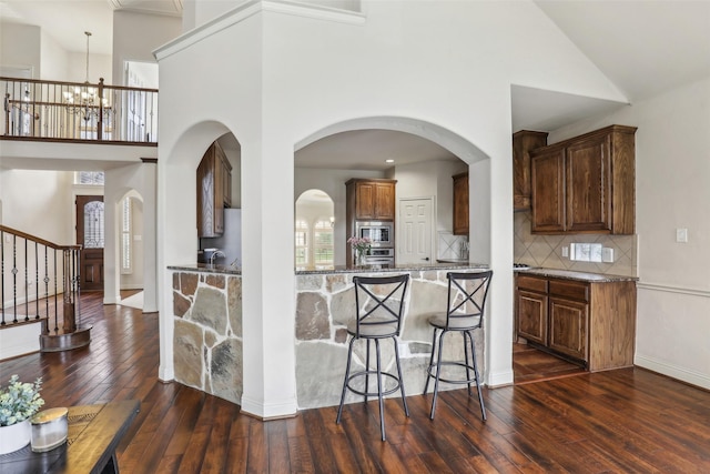 kitchen featuring a high ceiling, an inviting chandelier, and dark wood-style floors