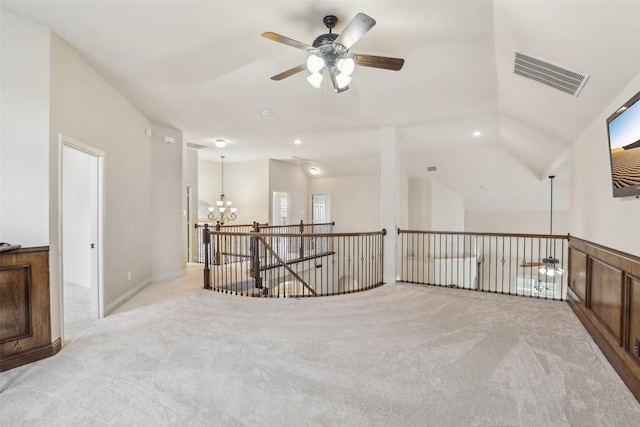carpeted empty room featuring ceiling fan with notable chandelier and visible vents