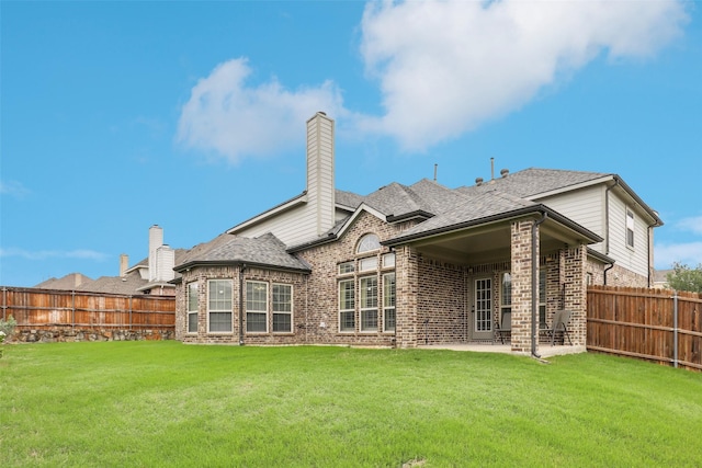 rear view of house with brick siding, a fenced backyard, a chimney, a patio area, and a lawn