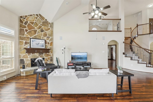 living room featuring a fireplace, high vaulted ceiling, stairway, arched walkways, and a ceiling fan