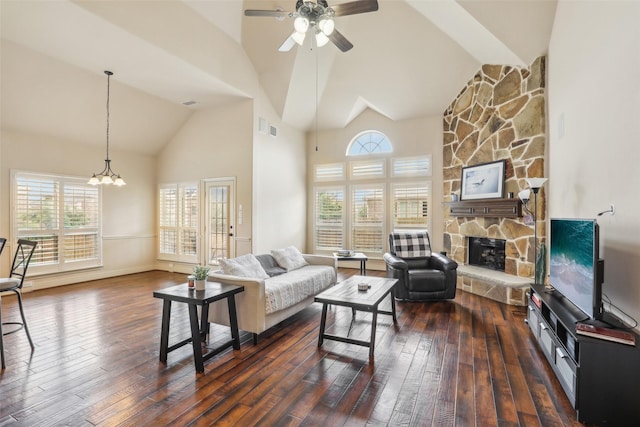 living area featuring plenty of natural light, a fireplace, high vaulted ceiling, ceiling fan with notable chandelier, and dark wood-style floors