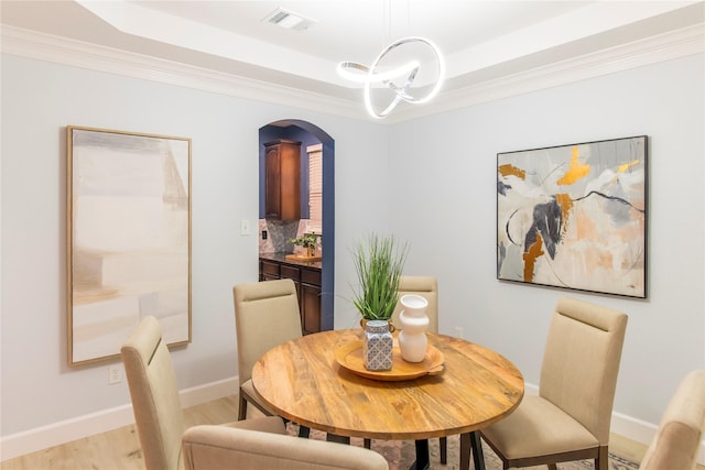 3501 Washington Dr, Frisco, TX 75034 - dining area with a tray ceiling, light wood finished floors, ornamental molding, arched walkways, and baseboards