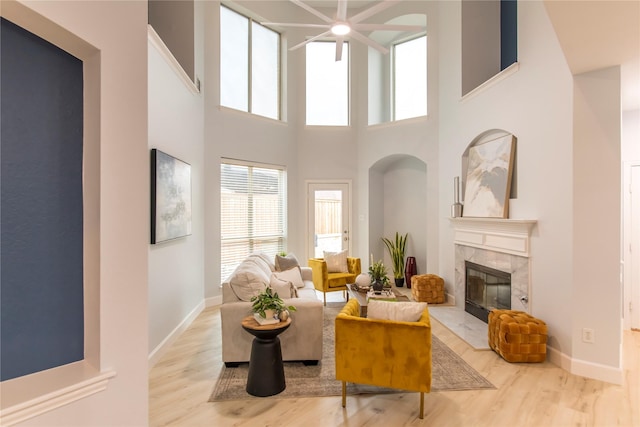 3501 Washington Dr, Frisco, TX 75034 - living room featuring wood finished floors, a high end fireplace, a towering ceiling, baseboards, and a ceiling fan