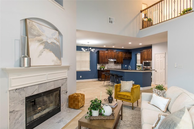 3501 Washington Dr, Frisco, TX 75034 - living room with a high ceiling, a premium fireplace, light wood-type flooring, a chandelier, and recessed lighting