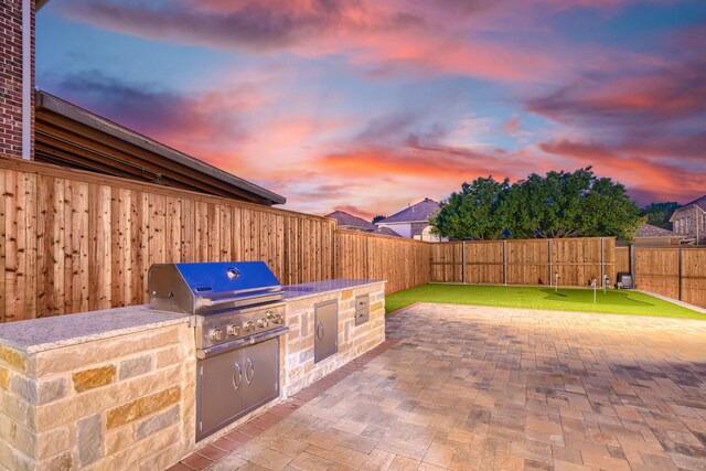 3501 Washington Dr, Frisco, TX 75034 - patio terrace at dusk featuring a grill, a fenced backyard, exterior kitchen, and a putting green
