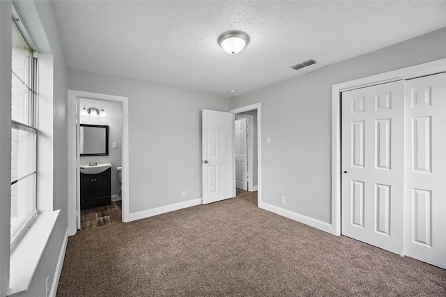 unfurnished bedroom featuring visible vents, a closet, baseboards, a textured ceiling, and carpet flooring