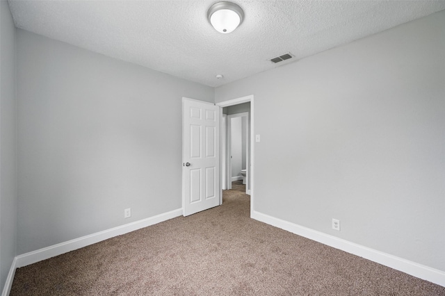interior space featuring a textured ceiling, visible vents, baseboards, and carpet